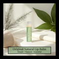 Natural lip balm on a light surface with green leaves and a woven basket in the background